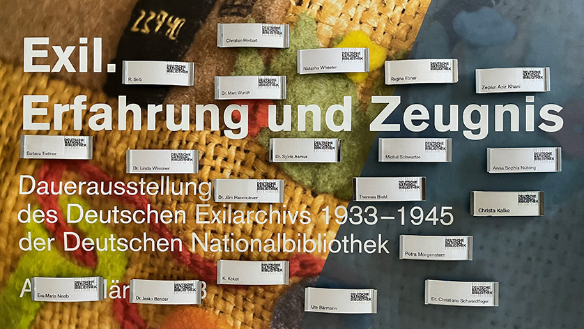 Die Namensschilder der Mitarbeiterinnen und Mitarbeiter des Deutschen Exilarchivs 1933–1945; im Hintergrund das Plakat der Dauerausstellung