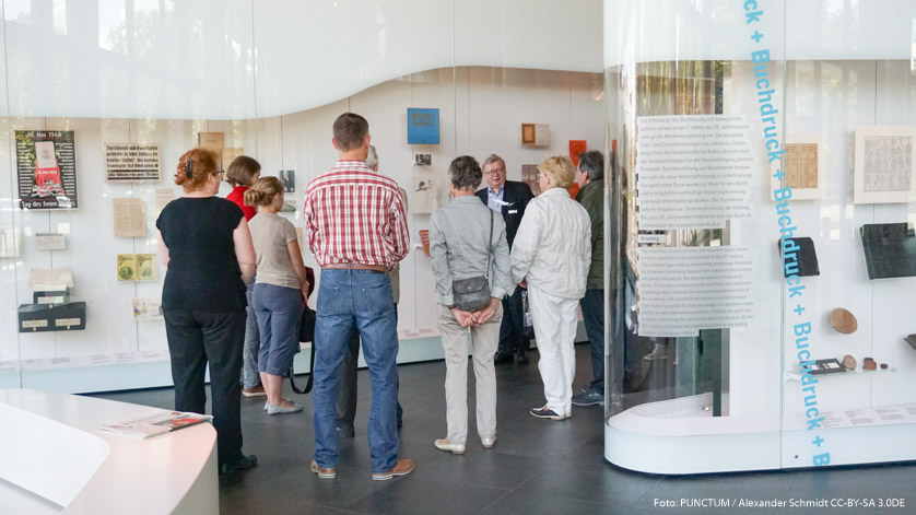 Eine Gästegruppe vor Vitrinen der Ausstellung "Zeichen - Bücher - Netze" des Deutschen Buch- und Schriftmuseums in Leipzig