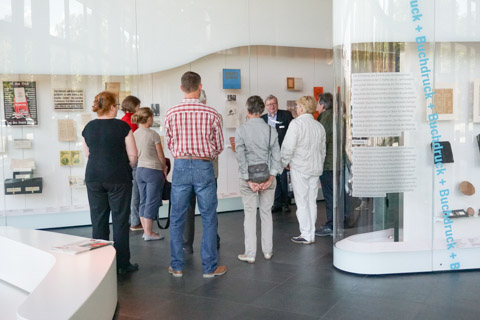 Eine Gästegruppe vor Vitrinen der Ausstellung „Zeichen - Bücher Netze“ des Deutschen Buch und Schriftmuseums in Leipzig