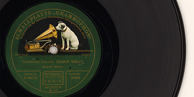 Bildausschnitt der Schellackplatte „Eisenbahn - Parodie“ von Rudolf Mälzer; hergestellt von der Deutschen Grammophon Aktiengesellschaft Berlin mit der für sie typischen Fotomontage „Hund guckt in ein Trichtergrammophon“