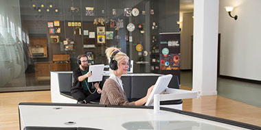 Eine Frau und ein Mann nutzen die Hörstationen im Ausstellungsbereich des Deutschen Musikarchivs