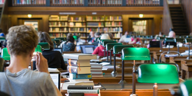 Ein Benutzer im geisteswissenschaftlichen Lesesaal der Deutschen Nationalbibliothek in Leipzig vor einem Stapel Bücher und seinem Notebook Ein Benutzer im geisteswissenschaftlichen Lesesaal der Deutschen Nationalbibliothek in Leipzig vor einem Stapel Bücher und seinem Notebook