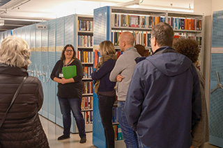 Besuchergruppe mit Bücherregalen im Hintergrund, eine Gästeführerin erläutert das Magazin der Deutschen Nationalbibliothek in Frankfurt am Main